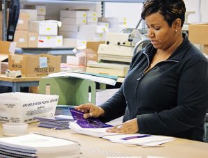 An Ironmark employee inserting printed collateral into envelopes