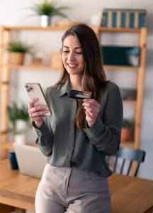 A woman using a smartphone and holding a credit card