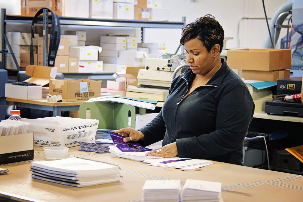 An Ironmark employee inserting printed collateral into envelopes