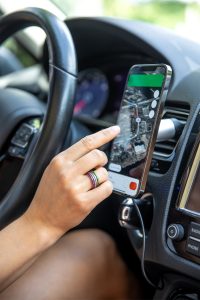 A woman using a smart phone mounted to the dashboard of an automobile
